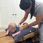 Dr Kim adjusts an infant on her table using the webster technique. There are benefits to pediatric chiropractic care.