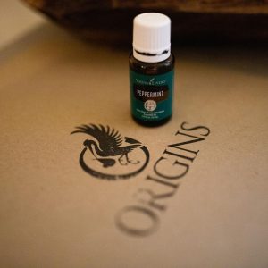A vial of peppermint oil sits on a folder that says "Origins".